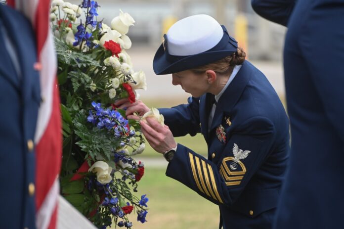 Coast guard member arranges flowers at a memorial service in Jacksonville